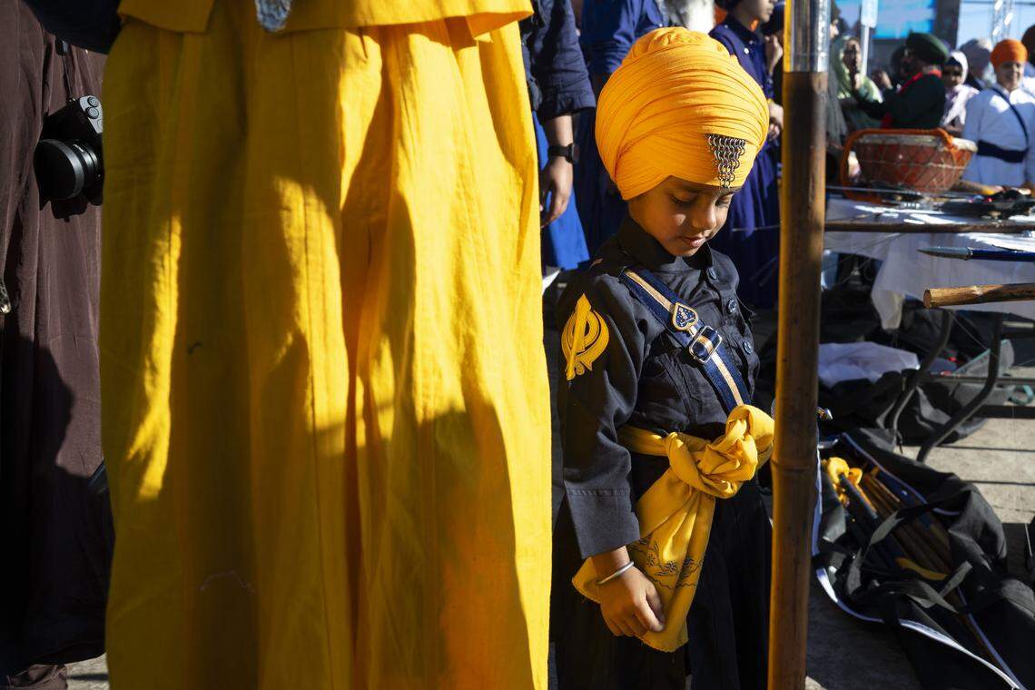 A child waits before a performance of gatkha, a martial art involving swords, before the Nagar Kirtan, also known as the Sikh Parade, in Sutter County on Sunday, Nov. 2, 2025.