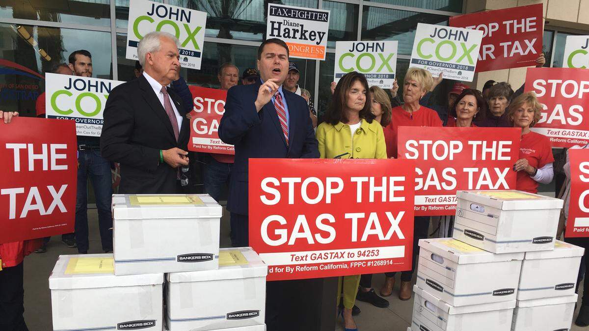 Proposition 6 leader Carl DeMaio, center, and Republican gubernatorial candidate John Cox, left, stand in front of signed petitions to get the measure on the Nov. 6 ballot in San Diego in April.