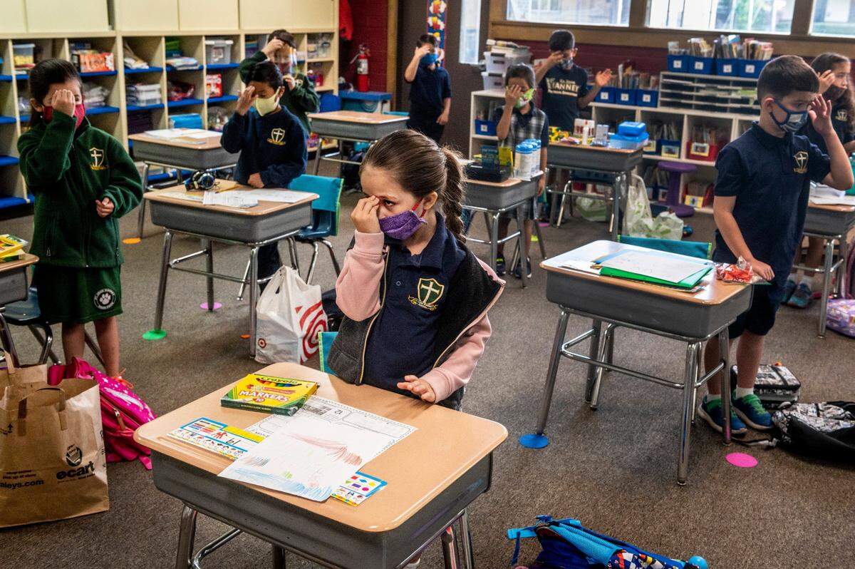 First-grader Amelia Riley, center, makes the sign of the cross with her classmates before snack time during the first day of on-campus instruction at St. John Vianney School in Rancho Cordova on Monday, Sept. 14, 2020. The school is one of 19 private schools – 16 run by the Catholic diocese – in Sacramento County granted waivers last week allowing in-person teaching during the coronavirus pandemic.