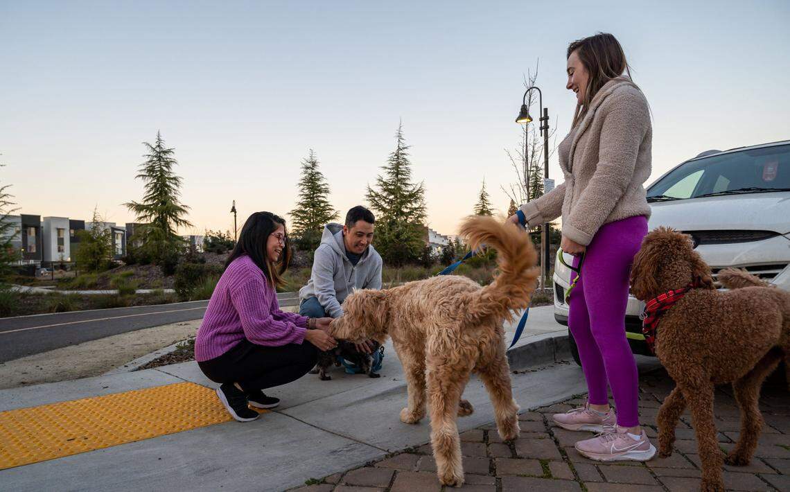 Jackie Jee, left, and her husband, Eric Jee, talk with neighbor Annie Rothschild while all out walking their dogs on Cleat Lane outside Outside Olympians park on Thursday, Jan. 27, 2022, in Sacramento.