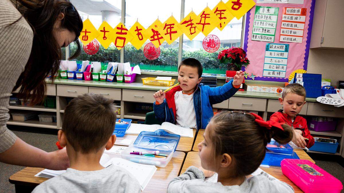 Eddie Guo, 5, center, raises his hand for help as kindergarten teacher Cai Li, far left, goes around the classroom to help students during instruction at the Buckeye Union Mandarin Immersion Charter School, a Chinese immersion program, on Sunday, Jan. 22, 2020, in El Dorado Hills.