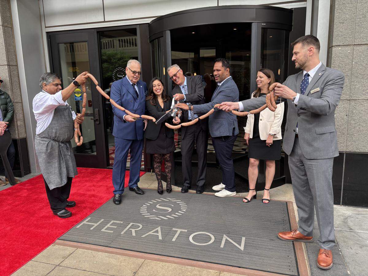 Jeroen Gerrese, general manager of Sheraton Grand Sacramento, stands second from left alongside others on-hand for a ribbon-cutting on March 31 to celebrate the newly-renovated hotel. Sausage links were cut to honor the site’s history as a public market.