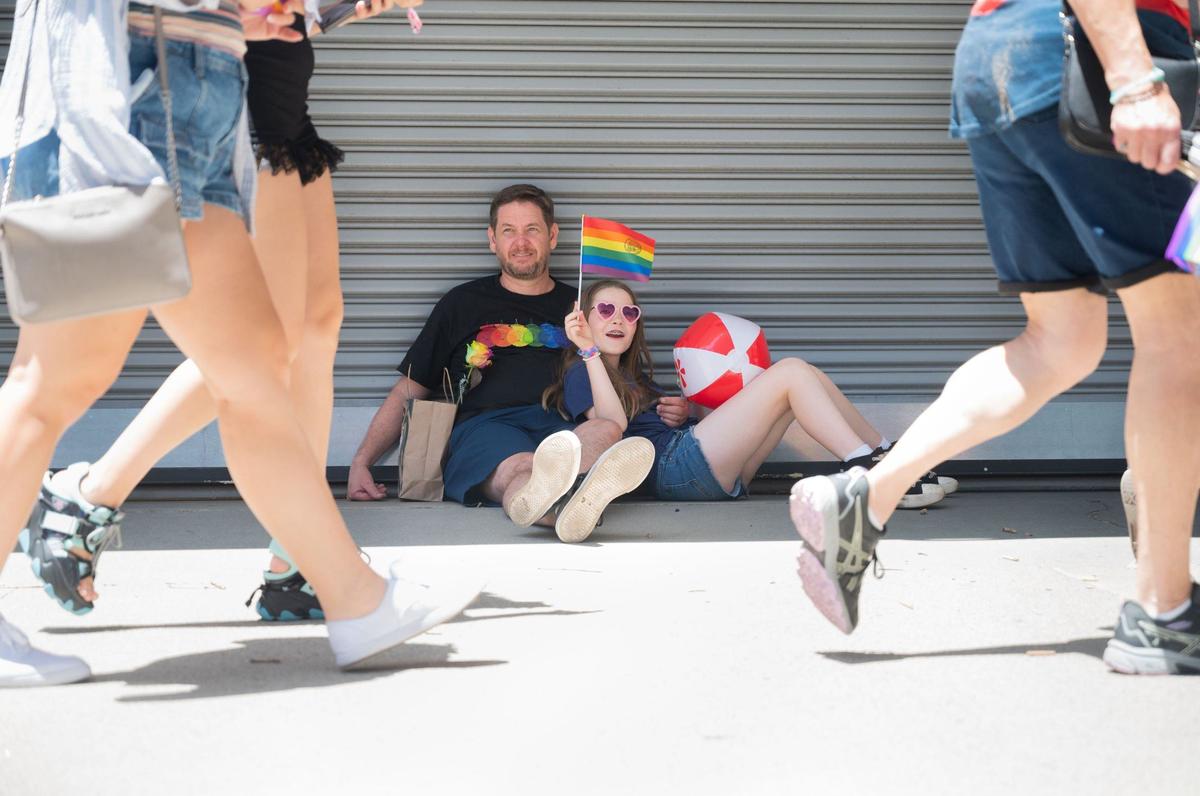 Jason McKnight, left, and Kris McKnight, 10, watch the Pride March in Sacramento on Sunday, June 9, 2024. Kris McKnight said this is her third time at Pride, and she appreciated the shade.