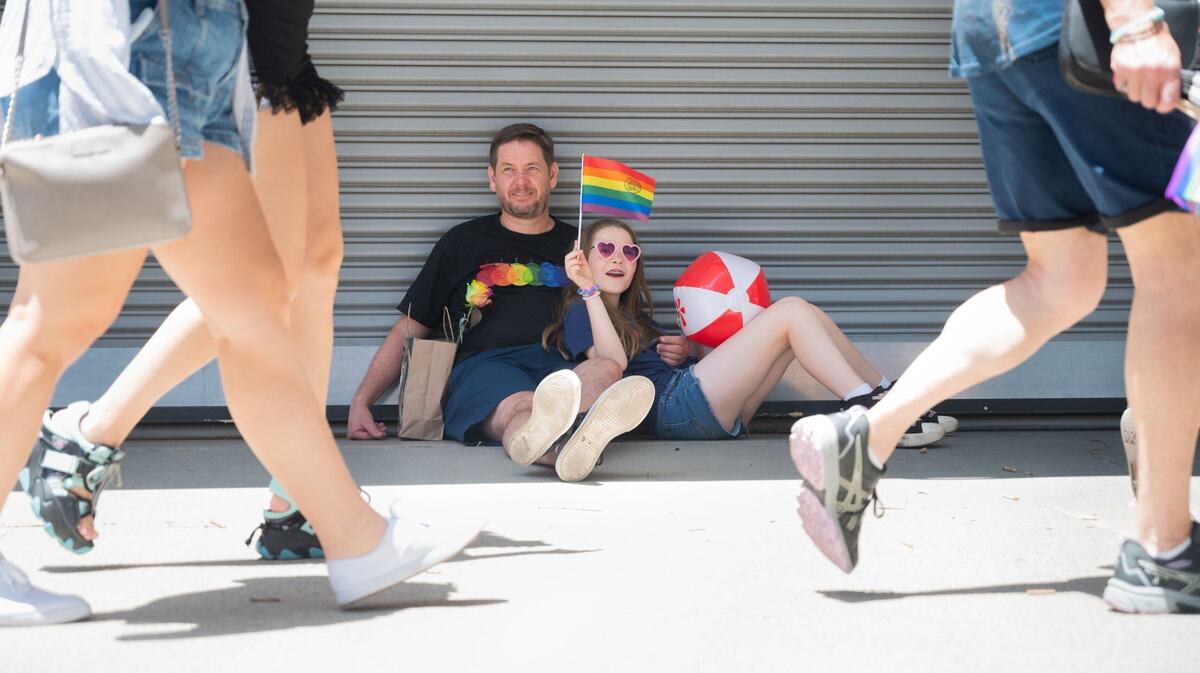 Jason McKnight, a la izquierda, y Kris McKnight, de 10 años, observan la Marcha del Orgullo el domingo. Kris dijo que esta era la tercera vez que asistía, y que disfrutó encontrar un espacio sombreado.