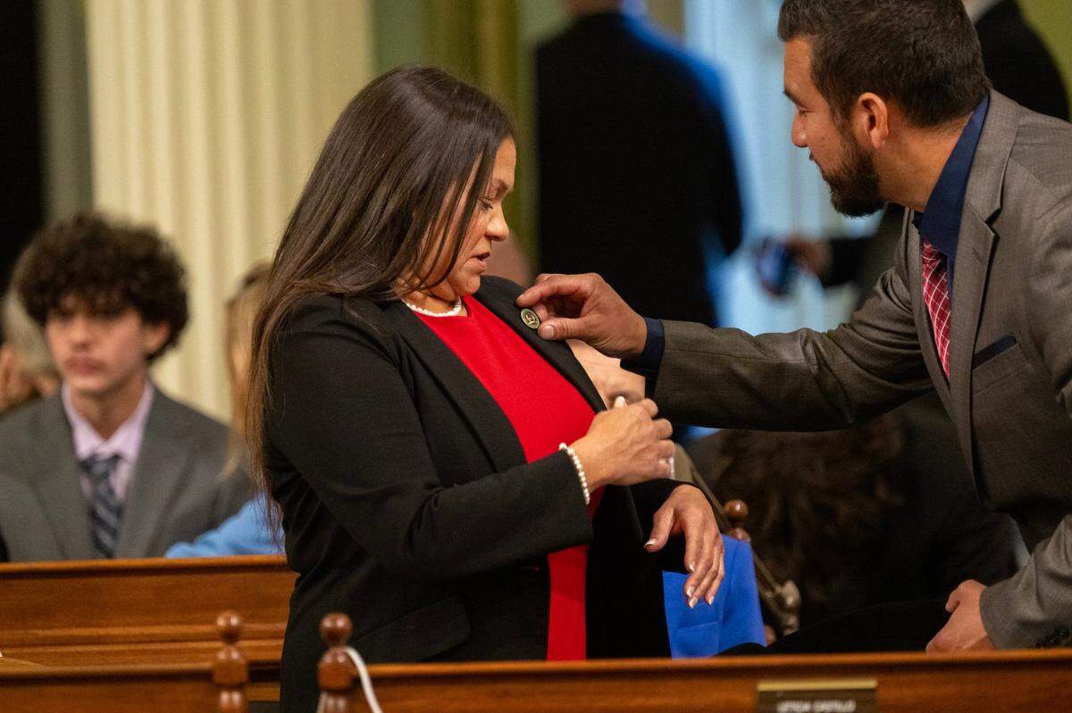 Robert Castillo adjusts the legislator pin of his aunt Assemblymember Leticia Castillo, R-Riverside, at the state Capitol on Monday during the Assembly’s first meeting of the new legislative session.