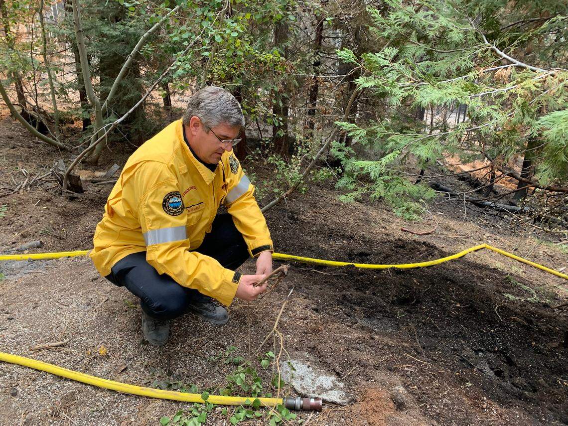 Eric Guevin of the Tahoe Douglas Fire Protection District examines ash from the Caldor Fire near a home on Reindeer Way in Christmas Valley, south of Lake Tahoe, on Friday.