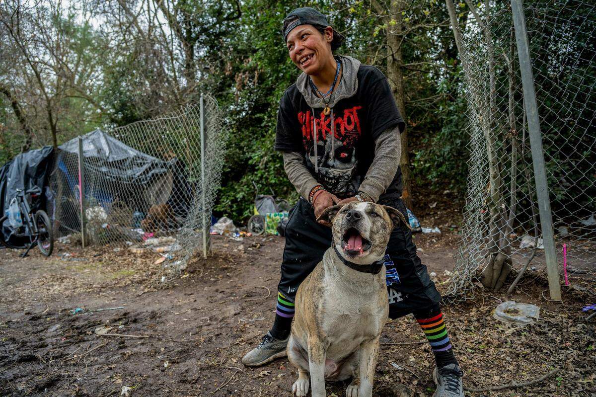 Regina Camacho, 41, holds her dog Goliath at her encampment on March 19 in South Natomas. She said she had been arrested in February and jailed for eight hours. Her dogs were thankfully safe with a friend, she said. “They threw away all my tarps, my blanket, my tent — didn’t have anything eight hours later when I got out of jail, but I had my dogs,” she said. “Now I’ve got a record — a misdemeanor, and homelessness and stuff — and I spent 41 years keeping my record clean. I was proud of that.”