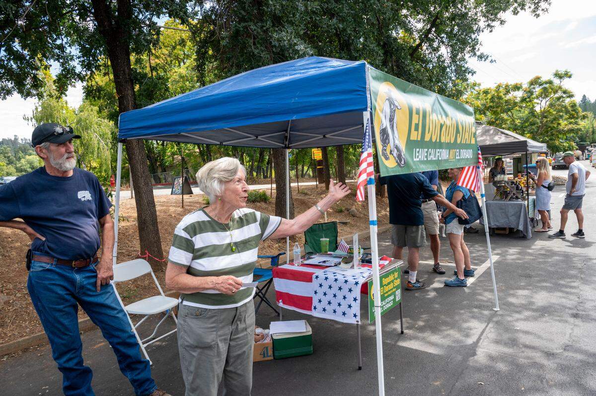 Sharon&nbsp;Durst, leader of the secessionist El Dorado state movement, waves to people at the group’s booth set up in a parking lot in Placerville on Sept. 13.