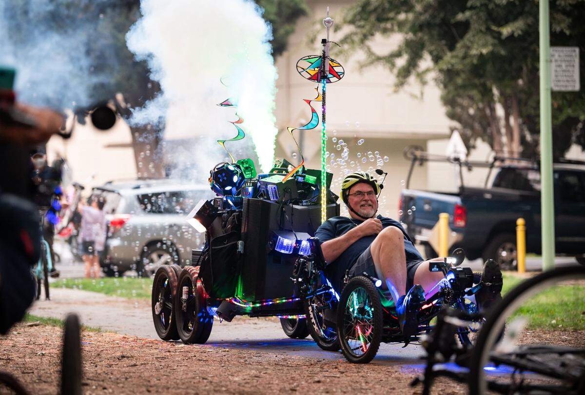 Dr. Bones, a San Jose Bike Party regular who traveled up for Bike Party Sacramento, pedals his mobile party which features a sound system, bubbles, scented fog and dance lights as bicyclists prepare to head out from Southside Park for the monthly Bike Party Sacramento ride Friday, Aug. 6, 2021.