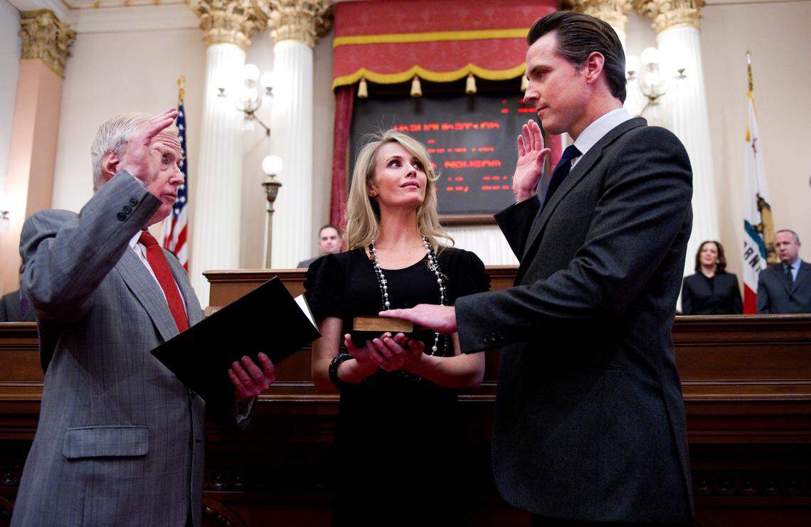 Jennifer Siebel Newsom holds the Bible as her husband Gavin Newsom is sworn in as lieutenant governor by his father, retired judge William Newsom, in the Senate chambers in 2011.