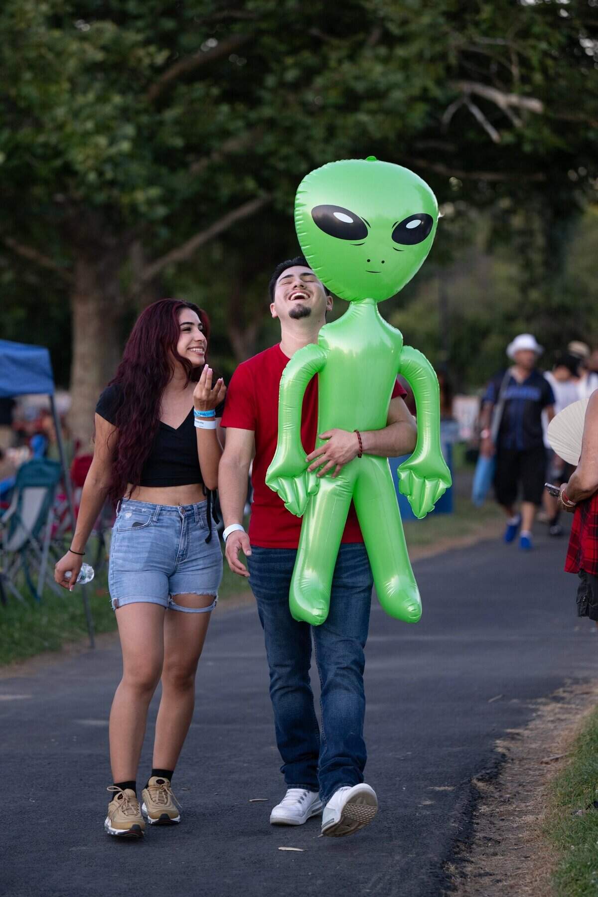 Oscar Ramirez, 21, and Joanna Alcarez, 20, walk with a blowup alien won at the Rancho Cordova Fourth of July celebration on Wednesday in Hagan Park.