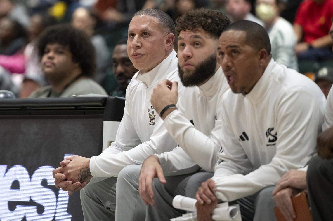 Sacramento State Head Coach Mike Bibby, left, sits next to his son, Associate Head Coach Michael Bibby, center, during a game between Sac State and Presbyterian at Hornet Pavilion in Sacramento on Nov. 16.