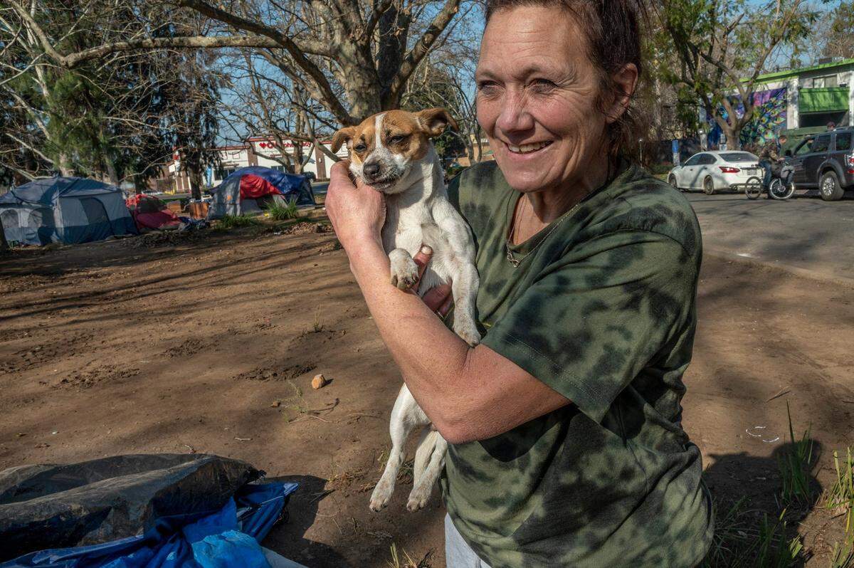Jamie Gardner, 55, hugs her dog as she explains how camping on a parcel of land near the corner of Fair Oaks Boulevard and Howe Avenue is much safer than camping along the river in Sacramento. “It’s creepy and it’s scary down there. I’ve been chased by knife point,” said Gardener Friday.