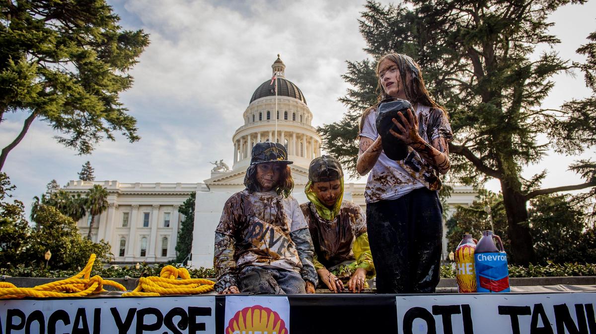 Student activists with Youth vs Apocalypse drenched themselves in mock oil while standing on an “oil tanker” in protest of CalSTRS at the Capitol in downtown Sacramento on Thursday, Jan. 30, 2020. The youth activist group called for the divestment of CalSTRS funds from oil companies, claiming it will affect climate change and their future.