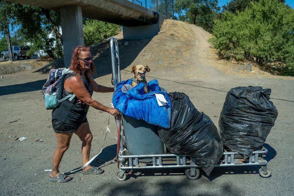 Chastity May, 50, pushes on Tuesday a cart carrying one of her dogs and items she was taking to a recycling center. She was one of the homeless residents who lost her trailer when the city of Sacramento removed Camp Resolution the day before. She was hoping to earn $15 so she could buy herself a meal.