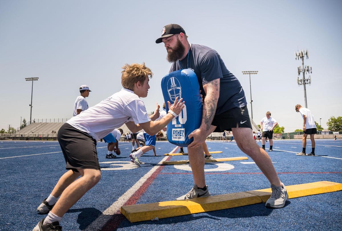 Cincinnati Bengals offensive tackle and former Bulldog Jonah Williams holds a pad as he works with youths running line drills at the Bulldogs Back Home 2023 football camp on Saturday, June 17, 2023, at Folsom High School. Fellow NFL players and former Bulldogs Jack Browning and Josiah Deguara — along with former pro Jordan Richards — worked alongside head coach Paul Doherty and other Folsom coaches at the camp