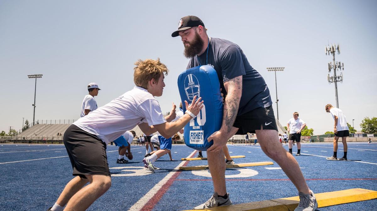 Cincinnati Bengals offensive tackle and former Bulldog Jonah Williams holds a pad as he works with youths running line drills at the Bulldogs Back Home 2023 football camp on Saturday, June 17, 2023, at Folsom High School. Fellow NFL players and former Bulldogs Jack Browning and Josiah Deguara — along with former pro Jordan Richards — worked alongside head coach Paul Doherty and other Folsom coaches at the camp