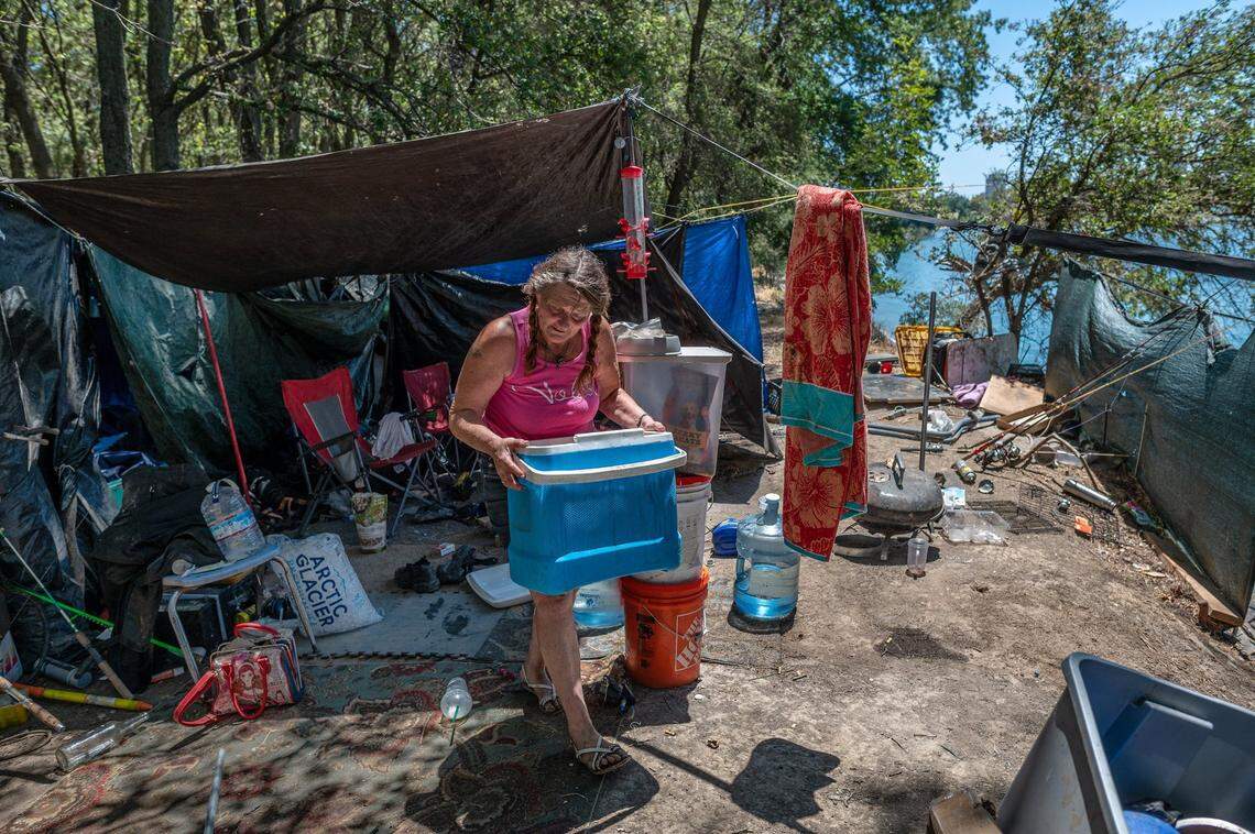 Catherine Roberts, 61, grabs an ice chest on July 6 at the camp where she’s lived for six years. She said she desperately wants an apartment for her and her dogs, but her social security check isn’t enough to pay for one.