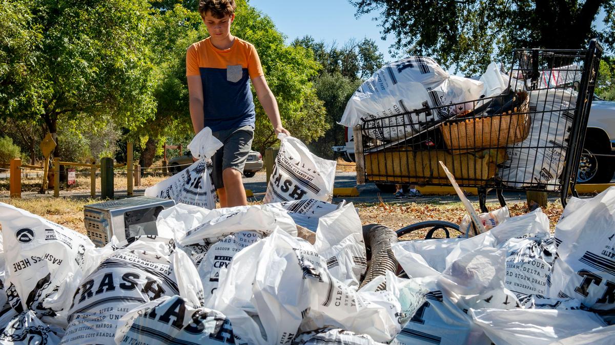 Parker Smith, 11, drops off bags of trash he and his dad collected during the Great American River Parkway Clean-Up in 2019. Sacramento is hosting a citywide series of events called the Great Sacramento Clean-Up on Saturday.