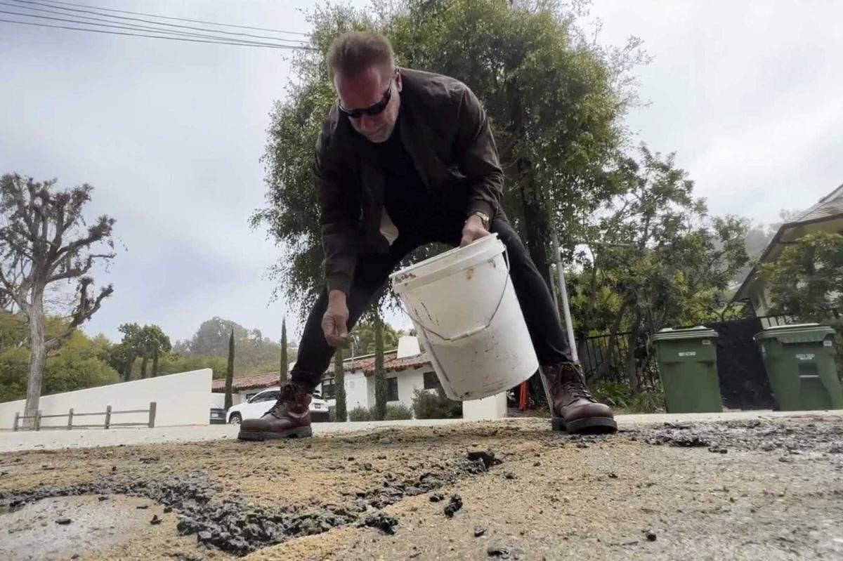 Former California Gov. Arnold Schwarzenegger is seen repairing a pothole on a street in his Los Angeles neighborhood on Tuesday. Fed up by an enormous pothole in his neighborhood, Schwarzenegger picked up a shovel and filled it himself.