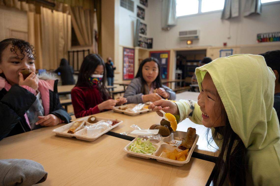 Emily Vang, 8, right, eats her school lunch other students in the cafeteria at Oak Ridge Elementary School in Oak Park on Wednesday, Feb. 22, 2023. Gov. Gavin Newsom announced Wednesday he was going to sign a bill that phases out ultra-processed foods from school meals by 2032.