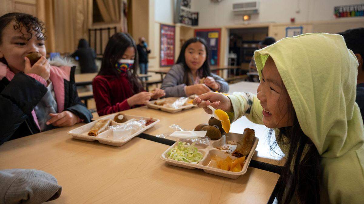 Emily Vang, 8, right, eats her school lunch other students in the cafeteria at Oak Ridge Elementary School in Oak Park on Wednesday, Feb. 22, 2023. Sacramento schools need federal support to buy locally grown produce, boost farmers and serve healthier meals.