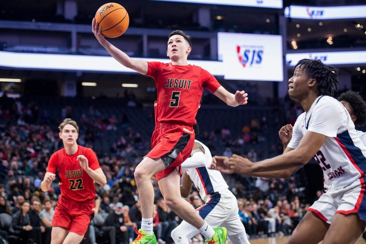 Jesuit Marauders guard Kevin Haupt (5) makes a layup past Modesto Christian Crusaders forward Kodey Weary (22) in the first half in CIF Sac-Joaquin Section Division I boys basketball championship on Saturday, Feb. 25, 2023, at Golden 1 Center in Sacramento. The Crusaders won 79-53.
