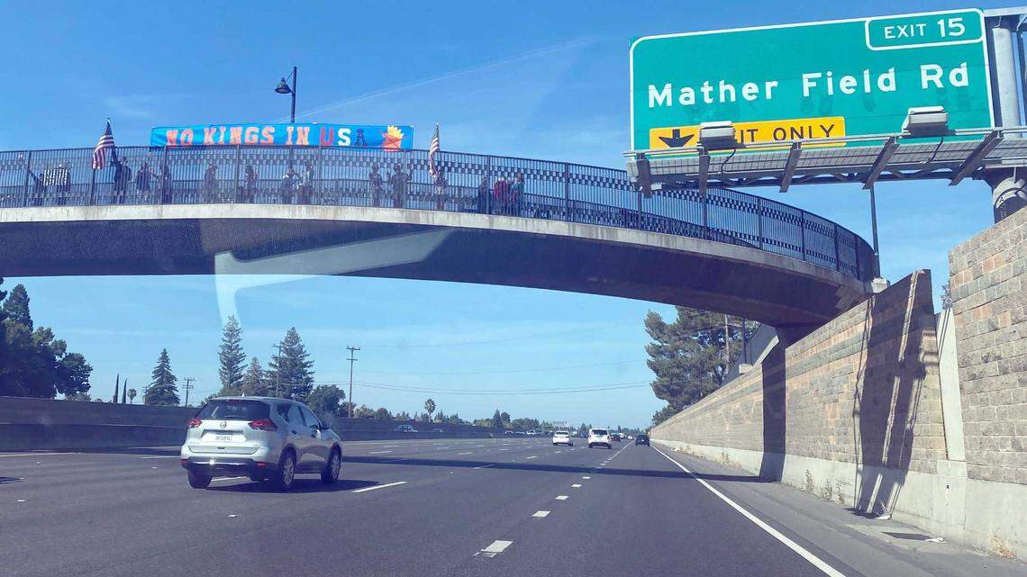 Protesters raise a banner saying “No Kings in USA” on a pedestrian overpass along Highway 50 near Mather Field Road in Rancho Cordova on Saturday, June 14, 2025. Protests are being organized at the California state Capitol in Sacramento as well as several other locations in the capital region.