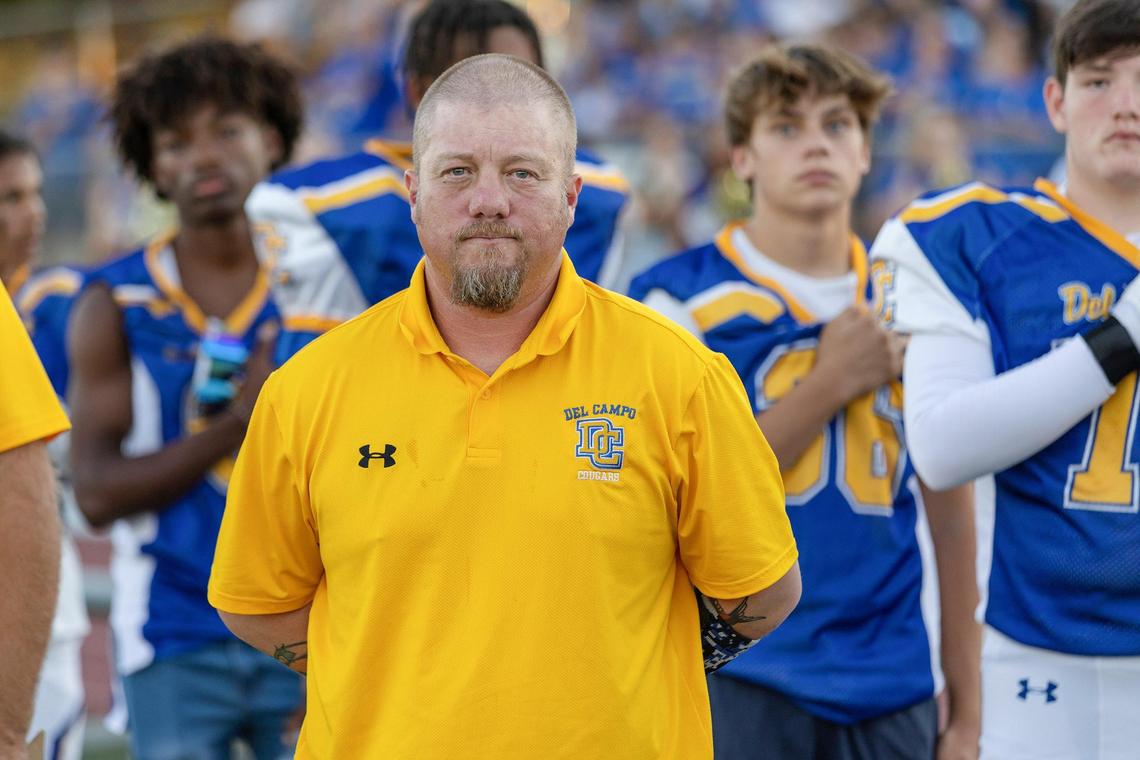 Del Campo coach Matt Costa stands on the sidelines during the playing of the national anthem before the game against the Bella Vista Broncos on Friday, Sept. 2, 2022, at Del Campo High School in Fair Oaks. The Cougars won 31-7.