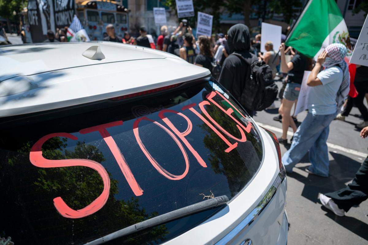 Demonstrators march past a vehicle with “stop ICE” written on the window as they protest against U.S. Immigration and Customs Enforcement in downtown Sacramento on Monday.