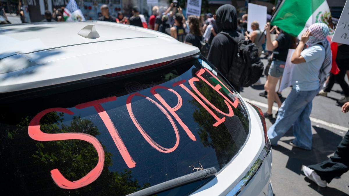 Demonstrators march past a vehicle with “stop ICE” written on the window as they protest against U.S. Immigration and Customs Enforcement in downtown Sacramento. A former Sacramento cop calls masked ICE agents cowards.