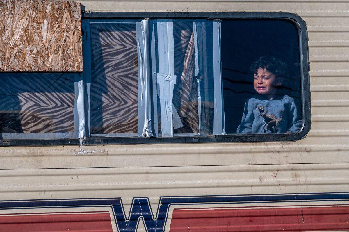 Atreus Hamilton, 2, cries as he looks out of a trailer while Sacramento city crews tow vehicles at a homeless encampment on Evergreen Street on Wednesday, Feb. 16, 2022. He is one of four children who live in the trailer along with his parents. His mother Summer Hamilton, 34, said she was given a three day extension.