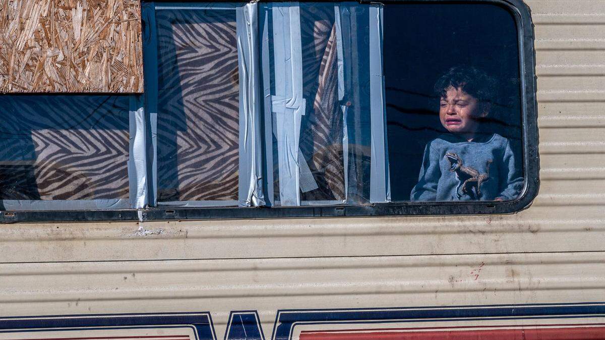 Atreus Hamilton, 2, cries as he looks out of a trailer while Sacramento city crews tow vehicles at a homeless encampment on Evergreen Street on Wednesday, Feb. 16, 2022. He is one of four children who live in the trailer along with his parents. His mother Summer Hamilton, 34, said she was given a three day extension.