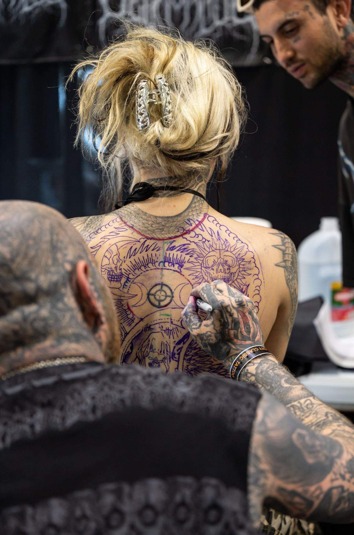 Rafel Delalande, with Seven Doors Tattoo of London, envisions a tattoo on Shy Sniders back during the Capitol City Classic Tattoo Conventions first day Friday, May 6, 2022, at the SAFE Credit Union Convention Center in downtown Sacramento.
