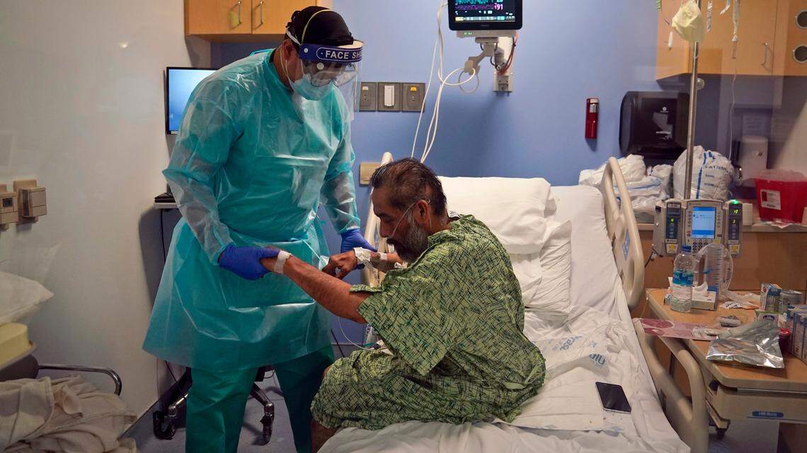 Physical therapist Daniel Lumbera helps a COVID-19 patient sit up on his bed at St. Joseph Hospital in Orange, Calif. Thursday, Jan. 7, 2021.