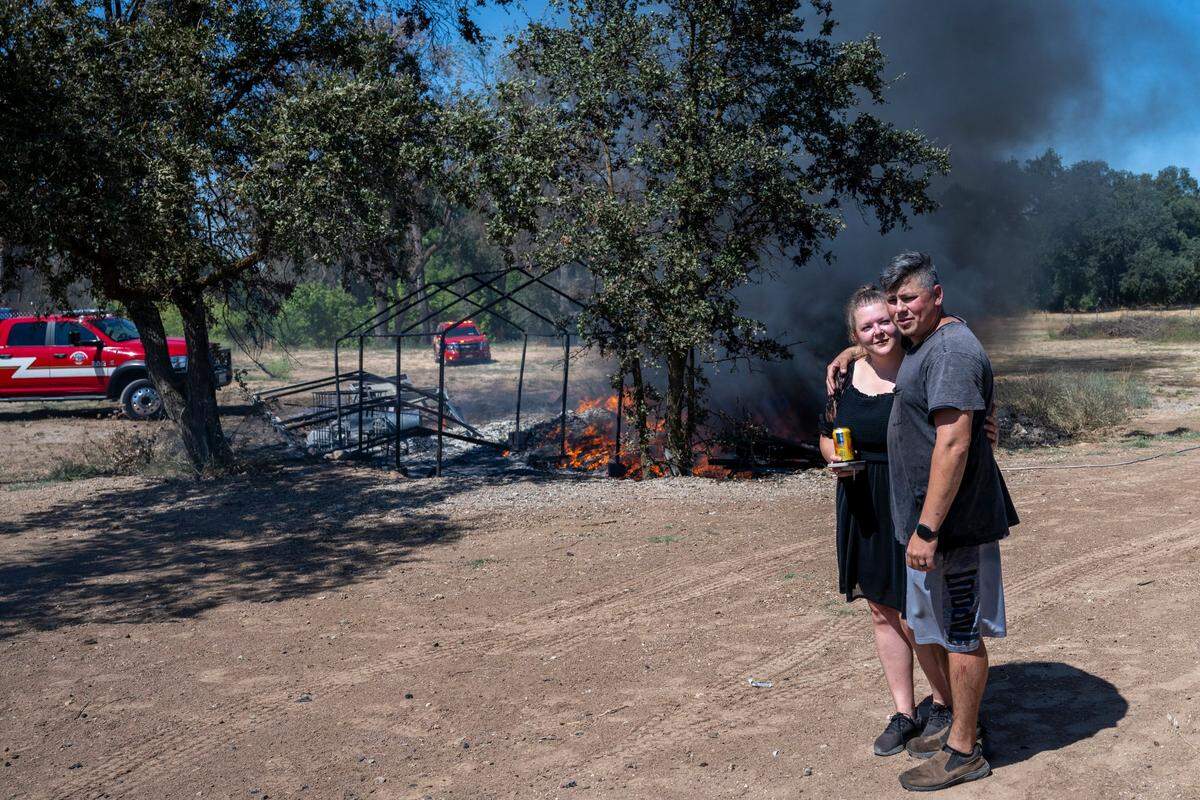 Kseniya and Slavik Donchenko embrace as the bee hive on their property burns from the Dry Creak fire in Rio Linda on Monday.