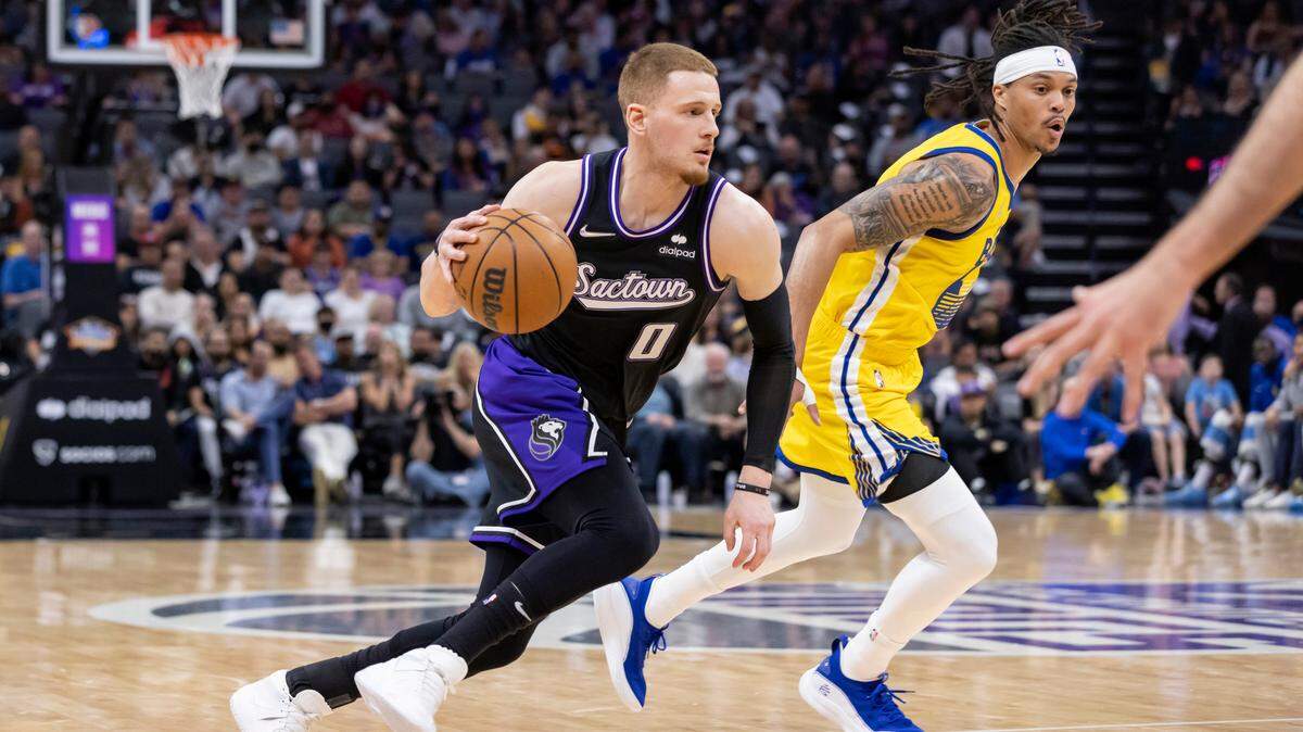 Sacramento Kings guard Donte DiVincenzo (0) drives to the basket past Golden State Warriors guard Damion Lee (1) and passes it to guard Jeremy Lamb (26) for an assist during the second quarter Sunday, April 3, 2022 during an NBA basketball game at the Golden 1 Center in Sacramento. DiVincenzo had 14 points. The Warriors defeated the Kings 109-90.