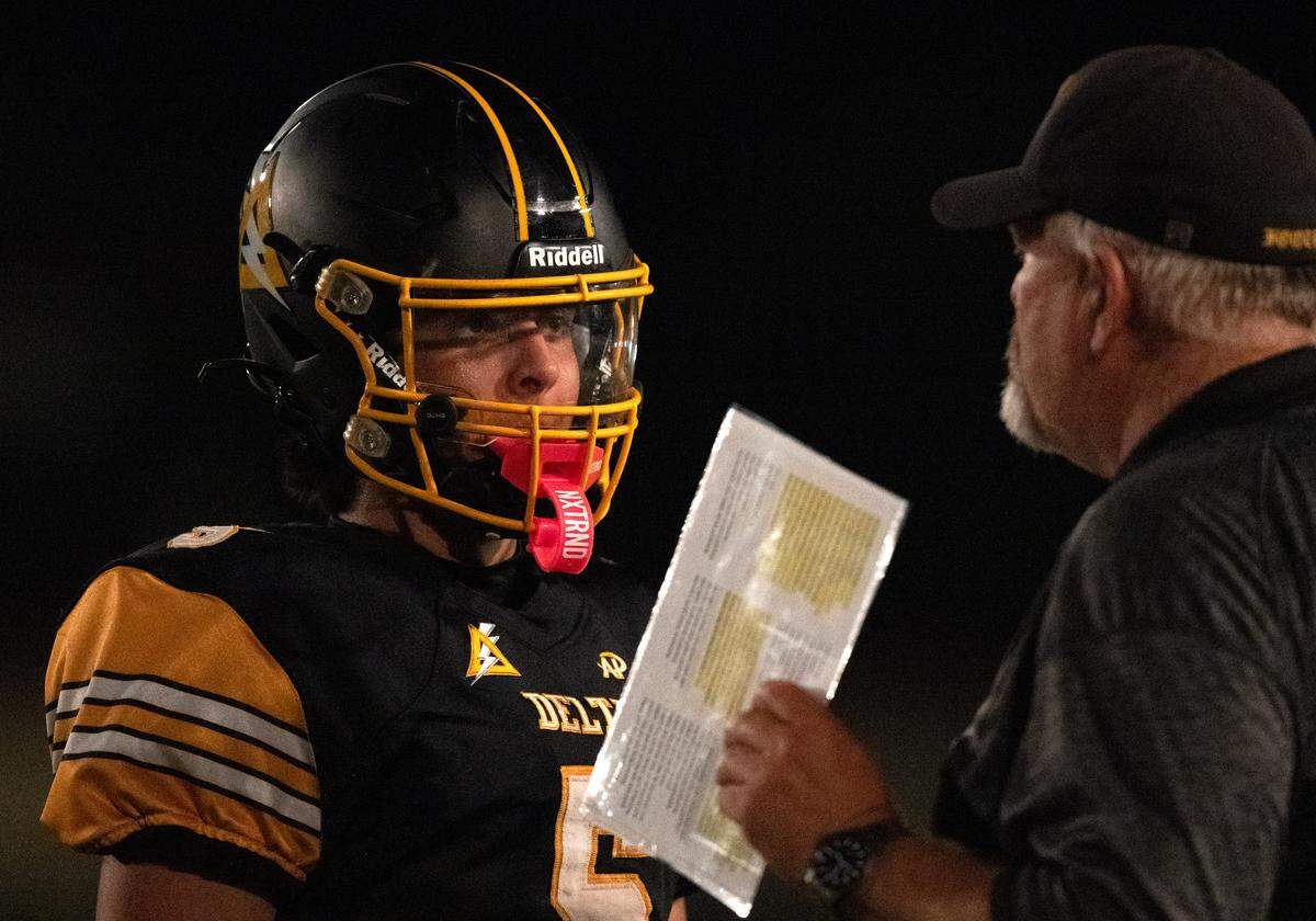 Delta coach Tim Rapp talks with with quarterback Chase Parkinson (5) on the sideline during an 8-man football game in Clarksburg on Friday.