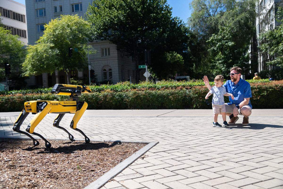 Graham Glazer, 2, center, great nephew of state Sen. Steve Glazer, D-San Francisco, and Grant Glazer, right, wave to Boston Dynamics’ robot dog Spot outside the state Capitol on Thursday. “Bye-bye robot dog,” the Glazers said as they walked away.
