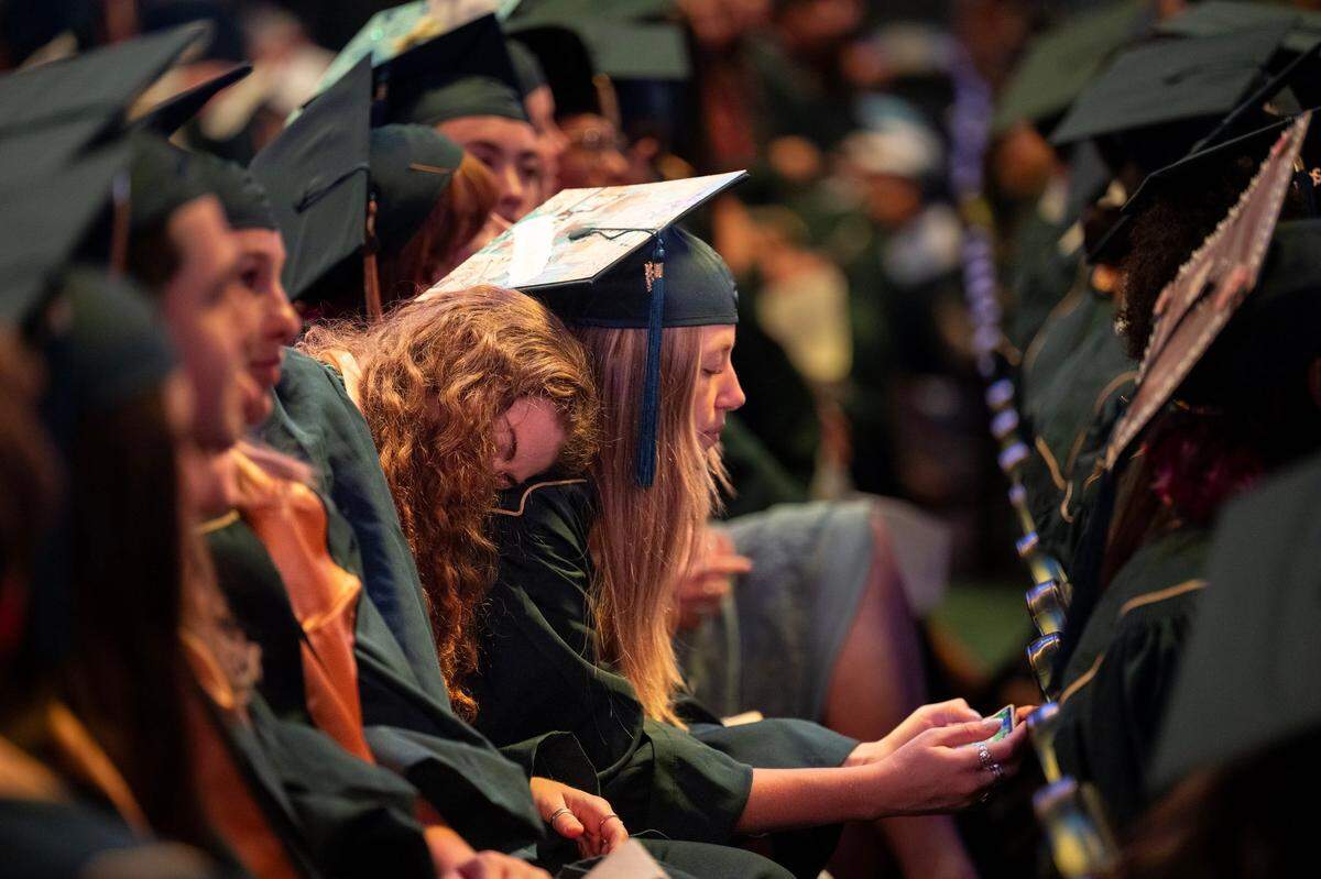Graduating UC Davis student Summer Camporesi leans on the shoulder of her friend Sierra Jean Barthr during the schoo’s 2024 commencement ceremony on Friday.