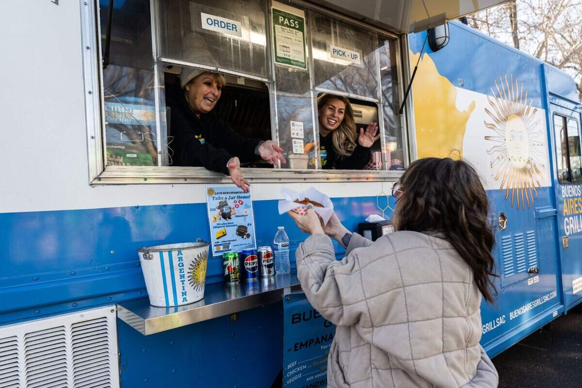 Francesca Martinelli hands a basket of empanadas to a longtime customer as daughter Estefania Bozzalla thanks her on earlier this month at the Midtown Farmers Market.