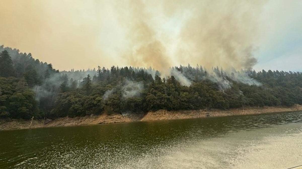 Smoke rises from the forest near the southeast perimeter of the Green Fire on Friday, as seen from a U.S. Forest Service boat on the Pit River looking northwest.