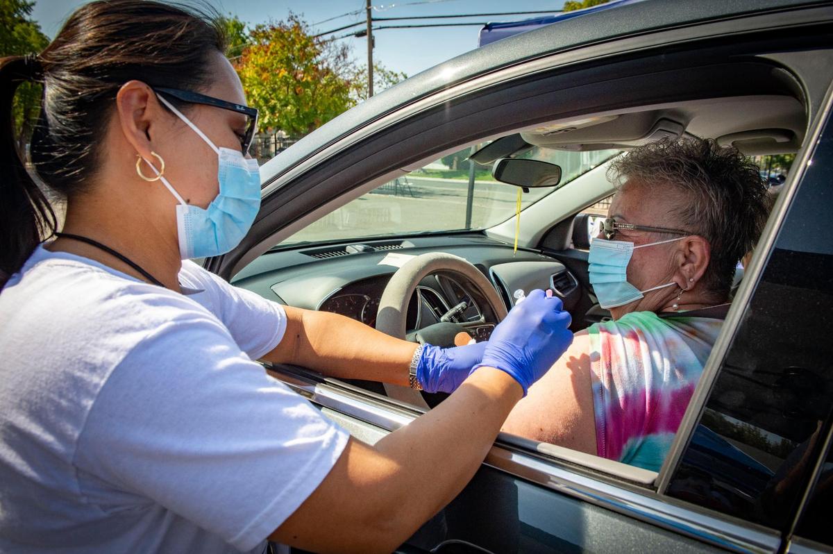 Barbara Corona sits in her car as Jane Peña, a registered nurse, administers a flu shot at a Sacramento County flu vaccine clinic hosted at The Church of Christ in South Sacramento on Saturday, Sept. 26, 2020.