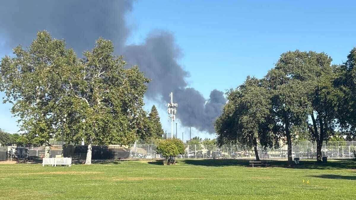 Black smoke rises from a vehicle fire at Truck Time Auto Wrecking on Recycle Road as seen from Hagan Community Park during Rancho Cordova’s Fourth of July celebration on Friday. Multiple vehicles stacked on racks caught fire after the blaze was reported about 5:45 p.m., and the smoke was visible across parts of the Sacramento region, including Arden Arcade and Rosemont.