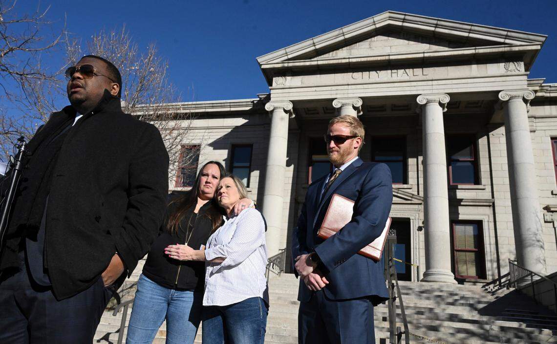 Attorneys Harry Daniels, left, and Kevin Mehr, right, stand as Kevin Dizmang’s daughter, Kenda James, and her mother, Linda Yutzy, hug during a press conference outside City Hall on Tuesday, Feb. 13, 2024, in Colorado Springs, Colo.