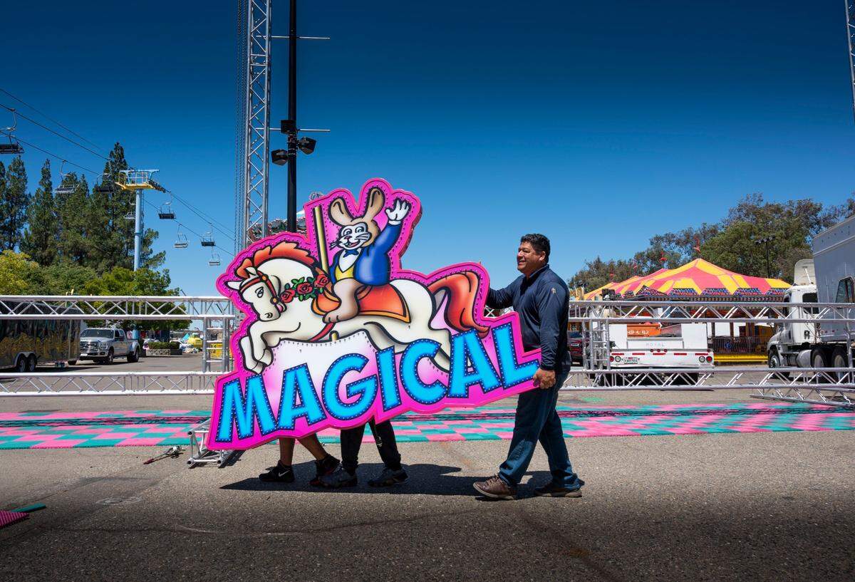 Javier Gamero, of Monterrey, Mexico, helps Butler Amusements Inc. co-workers move a sign that welcomes visitors at the California State Fair carnival area on Wednesday.
