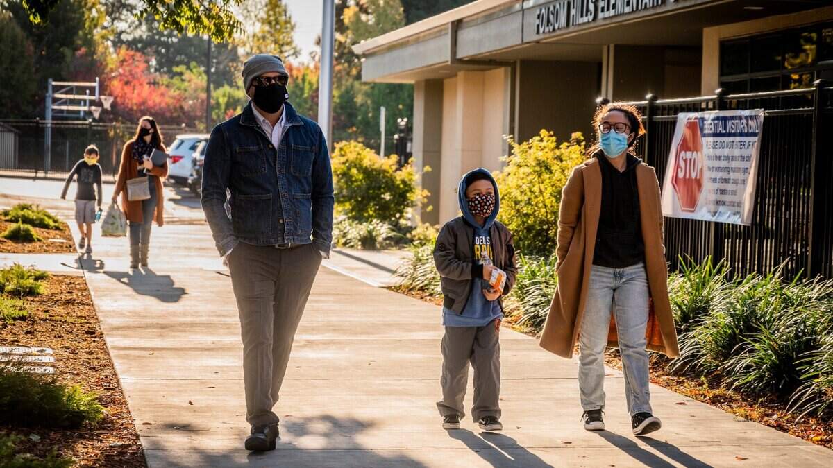 Florencio Sinogui, left, and Tyara Sinogui, right, walk their son Layden to school at Folsom Hills Elementary on Thursday, Nov. 12, 2020. It was the first day of in-class instruction for elementary schools in the Folsom Cordova Unified School District since they closed in March amid the coronavirus pandemic.