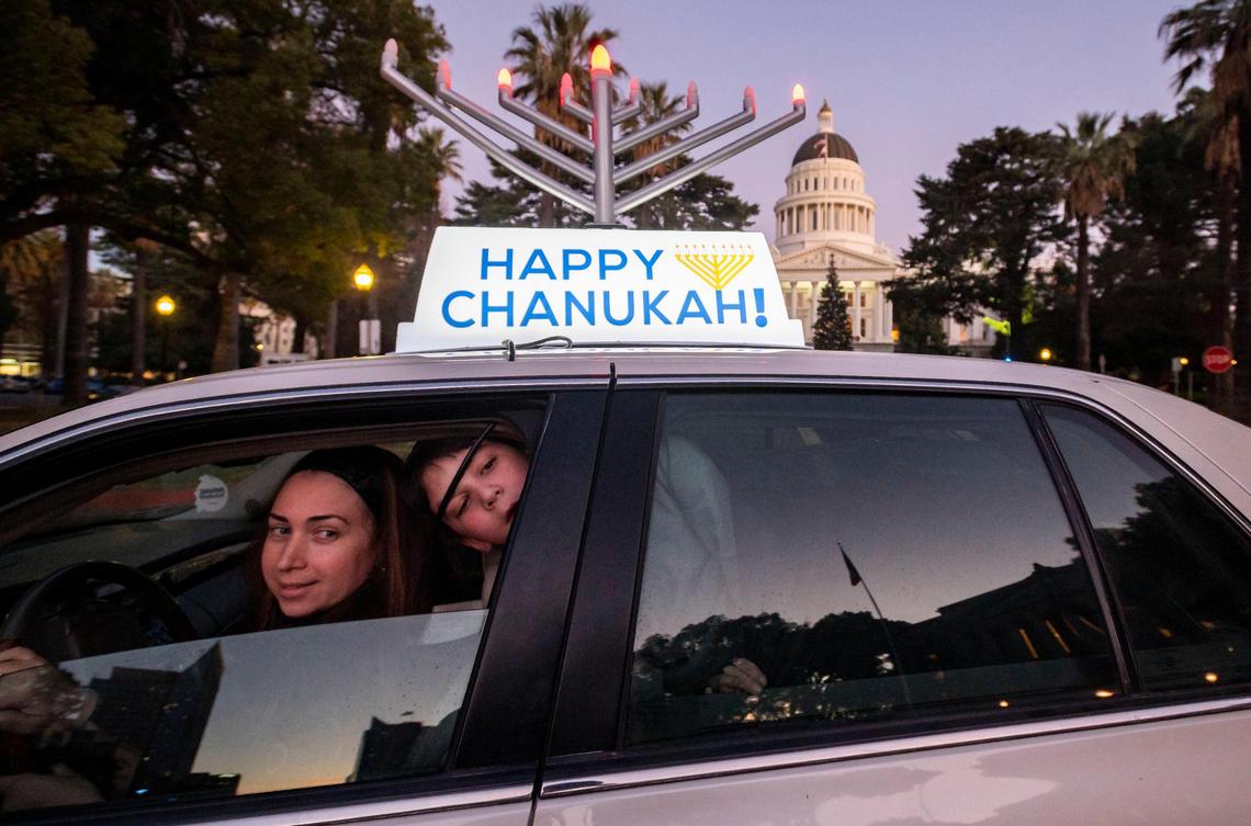 Naomi Cohen, left, and her son, Shalom Cohen, 8, wait with dozens of other cars to participate in a car menorah parade — coinciding with similar parades and distanced celebrations amid the pandemic around the world — before the lighting of a menorah at the Capitol on Thursday, Dec. 10, 2020, in Sacramento. Shalom said one of his favorite parts of the holiday is also celebrating his little sister’s birthday, who was “born on the third light.” The event was held by the Chabad Centers of the Sacramento Region, the area’s largest Jewish network. Hanukkah, the Jewish Festival of Lights that commemorates the victory of a militarily weak Jewish people who defeated the Syrian Greeks in ancient Israel, began Thursday and concludes Friday, Dec. 18.