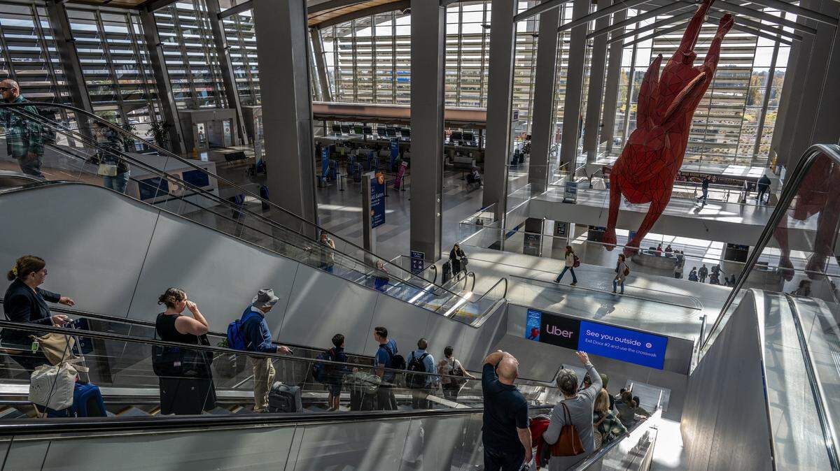 Travelers descend escalators as they make their way toward baggage claim at Sacramento International Airport’s Terminal B in November. The airport suffered flight delays Thursday after an AT&T fiber optic cable was cut, severing Internet service at the facility.