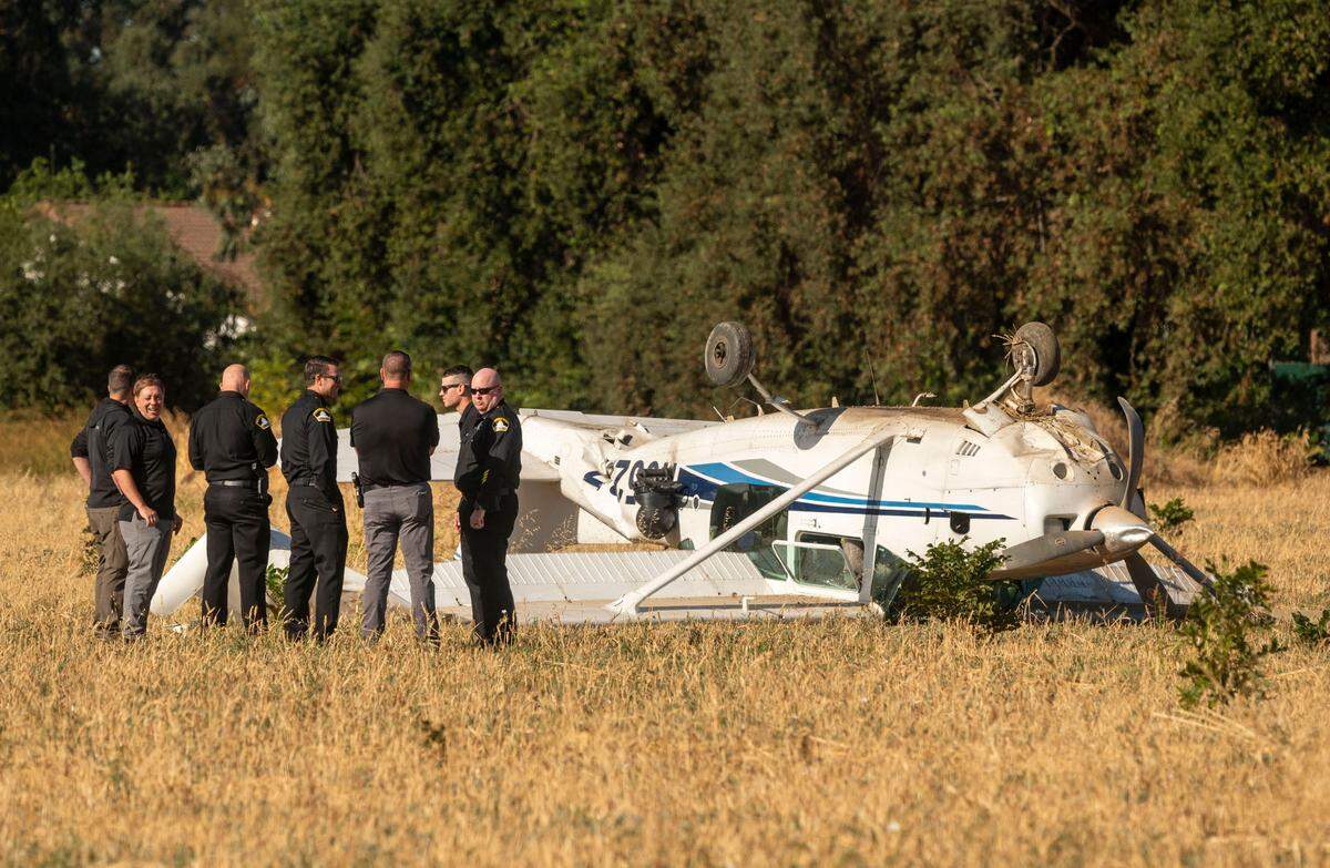 A Sacramento sheriff’s plane made an “emergency landing” and came to rest upside down in an open field near Village Parkway and Linden Road in West Sacramento on Thursday. The pilot, left, smiles while talking with sheriff’s department staff after walking away from the crash uninjured.